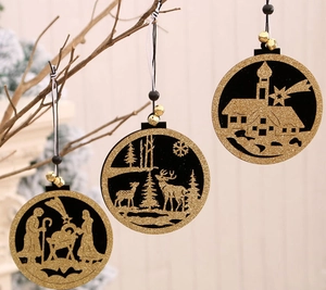 Drie houten holle kersthangers in zwart en goud hangend aan de takken van een kerstboom
