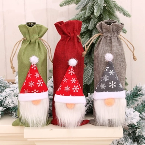 Three Christmas gnome wine bottle covers in red, green, and grey linen with snowflake hats