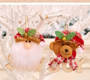 Detail of Santa and bear wooden ornaments with JOY and SNOW text on a Christmas tree