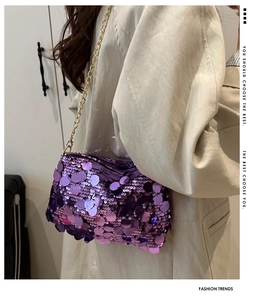 Detail shot of purple sequined handbag with gold chain strap on a stylish beige coat