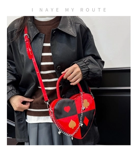 Detail of red and black heart-shaped crossbody bag with poker suit prints and silver chain