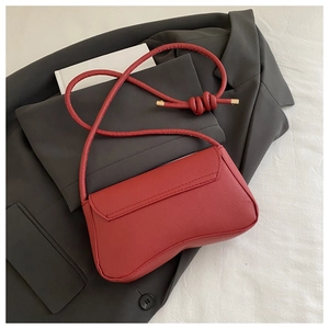 Detail of red crossbody bag with cross-grain leather texture and golden metal accents