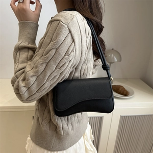 Minimalist black baguette bag for women with textured leather and knot strap detail