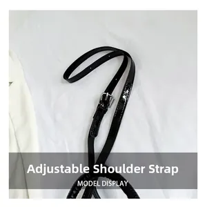 Detail of adjustable glossy black shoulder strap with silver buckle and neat stitching