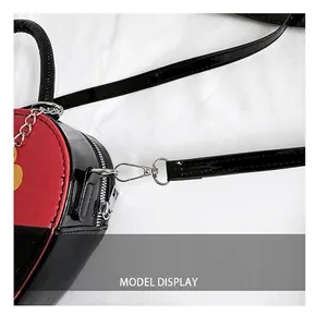 Detail of silver metal hook and strap on a heart-shaped glossy patent leather bag