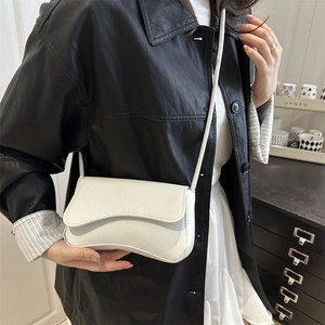 White textured leather crossbody bag with curved base shown on a female model