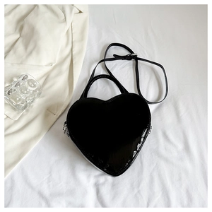 Close-up of glossy heart-shaped crossbody bag with metallic zipper and adjustable strap