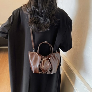 Sac nuage plissé marron foncé brillant de style vintage porté avec un manteau noir chic