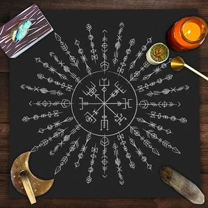 Top view of a black tarot altar cloth with white Vegvisir rune compass and mystic tools