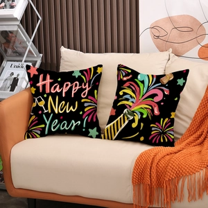 Set of two black Happy New Year pillow covers with colorful fireworks on a beige sofa