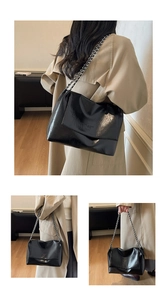 Detail of glossy black leather shoulder bag with silver chain strap and subtle logo