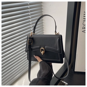 Detail of minimalist black handbag showing leather texture and gold twist lock closure