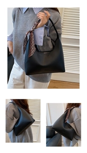 Détail d'un sac hobo en cuir noir avec une élégante poignée en écharpe de soie à motifs