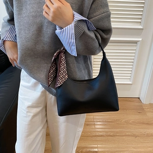 Black leather crescent underarm bag with decorative monogram silk scarf shown on arm