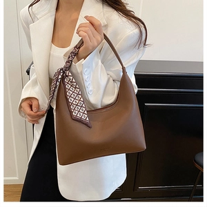 Close-up of brown leather hobo bag with a patterned silk scarf on the handle