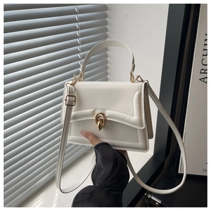 Detail of white faux leather handbag with elegant gold arch lock and top handle