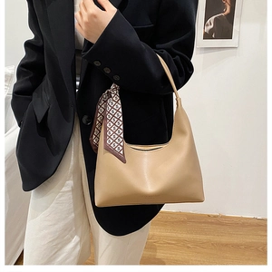 Detail of light brown retro shoulder bag with decorative silk scarf on model