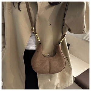 Detailed texture of brown suede hobo bag with gold buckle on a beige trench coat