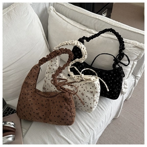 Trois sacs cabas en velours côtelé à pois et nœuds présentés sur un canapé blanc