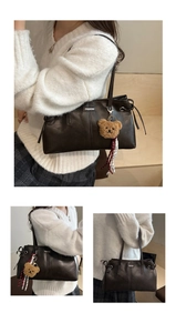 Détail d'un cabas vintage marron avec plaque en métal et breloque ours en peluche