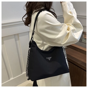Detailed view of black nylon shoulder bag with triangle metal logo and chain strap
