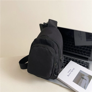 Sac bandoulière minimaliste en nylon noir avec double zip dans un décor de bureau