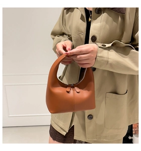 Detailed view of brown leather handbag with vertical stitching and smooth double zippers
