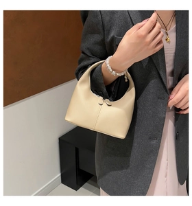 Close-up of cream leather mini hobo handbag featuring dual zipper and vertical stitching