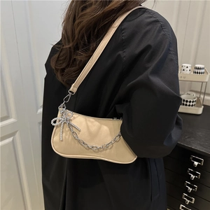 Sac bandoulière beige minimaliste avec chaîne argentée et nœud sur un mannequin