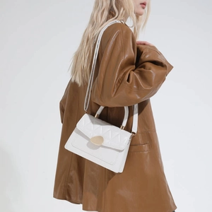 White quilted faux leather shoulder bag with gold metal clasp on a female model