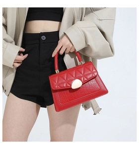 Detail of red quilted leather handbag with crocodile pattern and golden metal buckle
