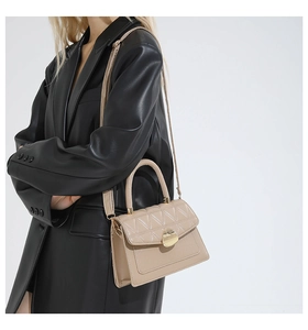 Gros plan sac bandoulière beige matelassé avec boucle en métal et poignée en cuir
