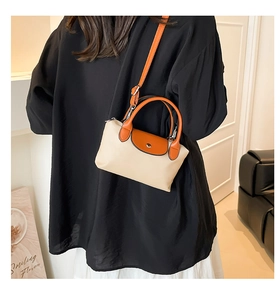 Détail du sac à main en nylon beige avec poignée en cuir orange et fermoir métallique