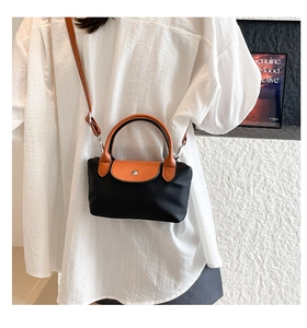 Détail d'un mini sac bandoulière en nylon avec poignées en cuir sur une chemise blanche