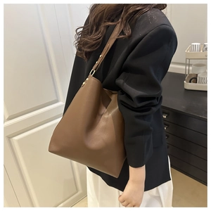 Detail of dark brown leather bucket bag with adjustable strap and gold metal hardware