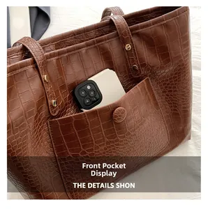 Detailed view of the brown crocodile embossed tote bag front pocket with smartphone