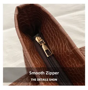 Close-up of premium crocodile texture and smooth gold metal zipper on brown tote bag