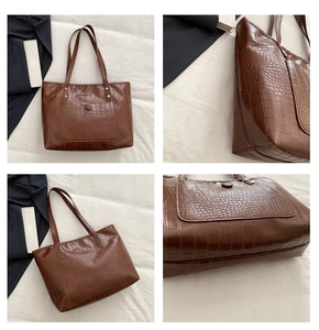Close-up of brown crocodile embossed faux leather tote bag with gold metal rivet details