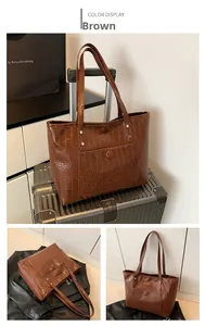 Detail of a brown tote bag with crocodile pattern texture and front pocket for travel