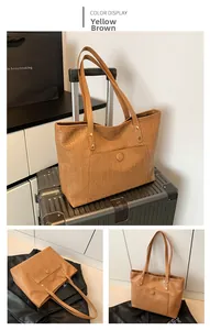 Detail of yellow-brown crocodile embossed tote bag with round buckle pocket on suitcase