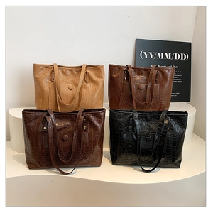 Detail view of four large crocodile pattern tote bags in khaki, brown, coffee, and black
