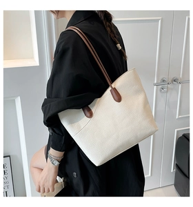 Detail of lychee textured cream tote bag featuring dark brown contrast shoulder straps