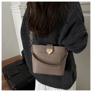 Detailed close-up of textured leather bucket bag with a golden heart-shaped metal buckle
