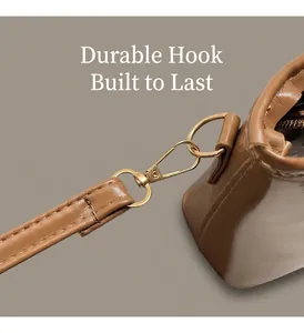 Close-up of golden metal lobster clasp and durable stitching on brown leather handbag