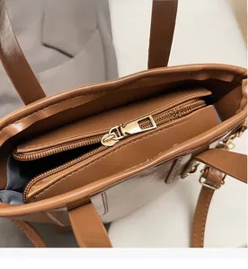 Detailed interior of brown leather handbag featuring smooth gold zipper and inner pocket