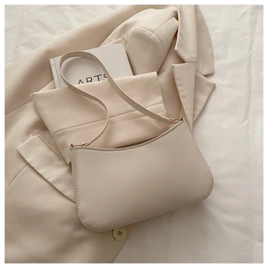 Detailed close-up of beige faux leather handbag with gold metal hardware and slim strap