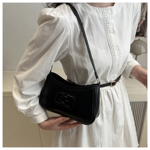 Detail of a black leather underarm bag featuring a prominent embossed G pattern design
