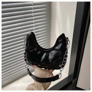Detail of glossy black patent leather crescent bag with chunky silver chain strap