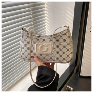 Detail of cream underarm bag featuring geometric patterns and embossed G logo on the front