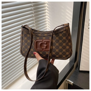Detail of vintage canvas baguette bag featuring brown embossed letter G and leather strap